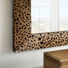 a leopard print mirror hanging on the wall next to a desk with a wooden box