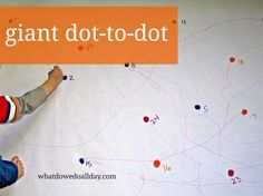 a young boy writing on a giant dot to dot wall