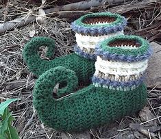 two knitted green and white booties sitting on the ground next to some grass