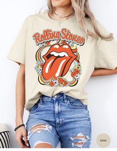 Step back in time and rock out in style with our Vintage Flower Rolling Stone Tee! 🌸🎸 This retro-inspired t-shirt features a classic Rolling Stone logo beautifully intertwined with vibrant flowers, capturing the free-spirited essence of rock 'n' roll and the timeless charm of the 70s. 🌼✨ Crafted from super-soft, high-quality fabric, this tee offers ultimate comfort and a perfect fit, making it an essential addition to your wardrobe. Whether you're heading to a concert, a festival, or just channeling your inner rock star, this tee will have you looking effortlessly cool and totally groovy. 🌟👕 Get ready to roll and bloom with style! 🌿🎶🛒 Spring Retro Print Tops For Streetwear, Vintage Spring Top For Concerts, Groovy Screen Print Tops For Spring, Retro Spring Tops For Concerts, Hippie Tops With Graphic Print For Spring, Hippie Style Graphic Print Spring Tops, Hippie Graphic Print Tops For Spring, Hippie Graphic Print Top For Music Festival, Retro Printed T-shirt For Spring