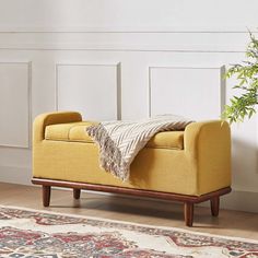 a yellow bench sitting on top of a wooden floor next to a potted plant