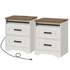 two white drawers with wooden top and one is plugged into an outlet in the wall