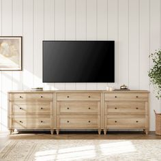 a living room with a large tv mounted on the wall next to a dresser and potted plant