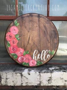 a wooden sign that says hello with flowers painted on the front and side of it