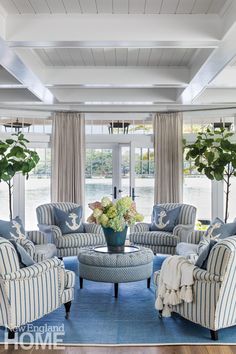 the living room is decorated in blue and white with striped chairs, sofas, and coffee table