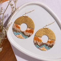 a pair of earrings sitting on top of a white plate next to a flower vase