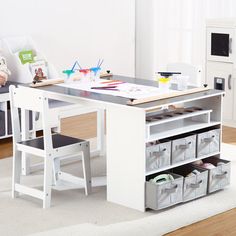 a child's desk and chair set up in a playroom with storage bins