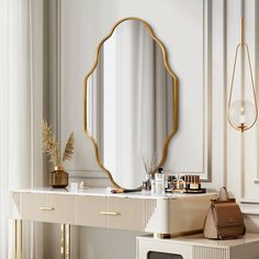 a dressing table with a mirror, purse and other items on it in front of a white wall