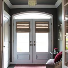 an entryway with two double doors and a chandelier hanging from the ceiling