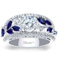 a diamond and blue sapphire engagement ring with leaves on the band, set in 18k white gold