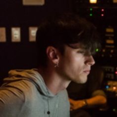 a young man sitting in front of a computer screen with his hand on the keyboard