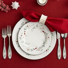 a place setting with red napkins, silverware and christmas decorations on the table