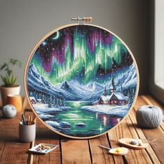 a cross stitch project with an aurora bore in the background