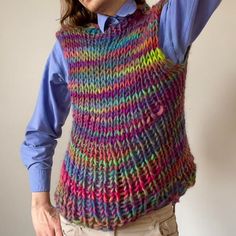 a man with long hair wearing a multicolored knitted sweater vest and hat