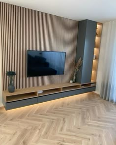 a living room with wood flooring and a large tv on the wall above it