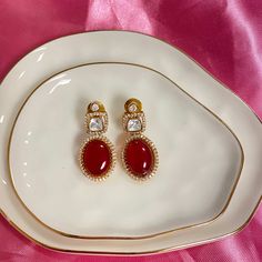 Discover the Ruby Pihu CZ Kundan Earrings, a masterpiece reflecting the grandeur of Indian and Pakistani jewelry traditions. These stunning red earrings are adorned with radiant ruby stones, framed by intricate CZ and kundan work, exuding timeless elegance. Perfect for any occasion, these ruby earrings add a touch of opulence to your ensemble. The impeccable craftsmanship and luxurious design make them a must-have accessory for any jewelry lover. Embrace the beauty and sophistication of South As Luxury Traditional Ruby Jhumkas, Polki Jewellery, Bangle Ring, Kundan Earrings, Pakistani Jewelry, Ruby Stone, Natural Stone Jewelry, Oxidised Jewellery, Ruby Earrings