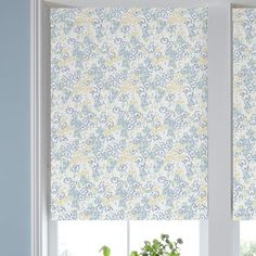 two windows with blue and yellow roman blinds in the window sill, one has a potted plant next to it