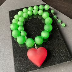 Destaca con este impresionante y único collar llamativo verde impreso en 3D. Diseñado con cuentas gruesas e inspirado en el icónico estilo Iris Apfel, este collar irradia elegancia, confianza e individualidad. El vibrante color verde añade un toque de frescura a cualquier conjunto, convirtiéndolo en un accesorio versátil y llamativo. La pieza central de este collar presenta un impresionante colgante de corazón rojo, que simboliza el amor y la pasión. Elaborado con tecnología avanzada de impresió Unique Green Resin Necklaces, Green Heart-shaped Beaded Necklace Gift, Green Heart-shaped Jewelry For Party, Unique Green Resin Necklace, Green Necklaces For Valentine's Day Party, Handmade Green Jewelry For Valentine's Day, Bold Resin Jewelry For Gifts, Bold Resin Jewelry For Gift, Green Heart-shaped Party Jewelry