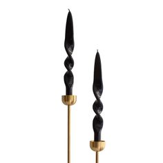 two black and gold candlesticks sitting next to each other on a white surface