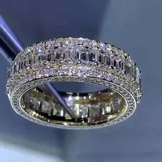 a diamond ring is being held up by a pair of tongs in front of a mirror