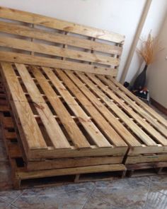 a bed made out of wooden pallets in a room with tile flooring and walls