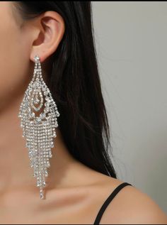 Make a dazzling statement with VALENTINA Chandelier rhinestone Statement Evening Earrings! These earrings are designed to captivate and command attention. Featuring clear rhinestones on a stunning silver base, they exude a sense of elegance and glamour. With a length of 5.9" (14.98cm) and a width of 1.8" (4.57cm), these earrings are designed to stand out and elevate your stage presence. The post back with a push back circle closure ensures a secure and comfortable fit, allowing you to strike you Glamorous Chandelier Earrings With Rhinestones, Glamorous Crystal Chandelier Earrings, Glamorous Crystal Chandelier Earrings With Rhinestones, Glamorous Crystal Chandelier Earrings With Bling, Dazzling Crystal Chandelier Dangle Earrings, Crystal Chandelier Dangle Earrings For Glamorous Events, Crystal Chandelier Drop Earrings With Rhinestones, Glamorous Crystal Chandelier Earrings For Glamorous Events, Dazzling Silver Chandelier Earrings With Crystals