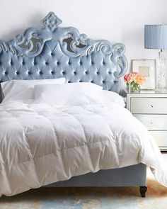 a bedroom with a blue headboard and white comforter on top of the bed