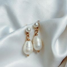 "Our \"Camden\" freshwater pearl dangle earrings are the perfect addition to any outfit. Dress them up for a special occasion or pair them with a pain white tee for an everyday look. PRODUCT DETAILS: ✩ 12mm real freshwater pearls ✩ hypoallergenic, nickel-free, faux pearl stud. Push back closure, backs included. ✩ 1 inch drop length, lightweight *sold in pairs CARE: All of our \"Camden\" earrings are made with real freshwater pearls. It is strongly recommended that you avoid exposure of your jewelry to water when swimming or showering, along with avoiding contact with chemicals or oils when applying perfume or lotion to the skin. It is best to remove your jewelry when engaging in physical activities or working out to avoid contact with sweat. Storing your jewelry in a box or sealed bag in a 14k Gold Filled Pearl White Dangle Pearl Earrings, Pearl Drop Earrings With Pearl Charm, Minimalist Teardrop Pearl Chain Earrings, Dangle Pearl Drop Earrings, Pearl White Earrings With Pearl Charm In 14k Gold, 14k Gold-filled Pearl White Earrings With Pearl Charm, Minimalist Pearl Drop Bridal Earrings, Minimalist Pearl Bridal Earrings With Matching Set, Pear-shaped Pearl Chain Earrings