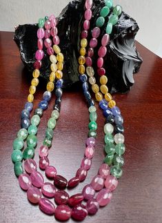 multicolored glass beads on a wooden table next to a black rock or sculpture