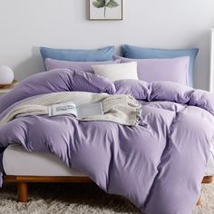 a bed with purple sheets and pillows in a bedroom