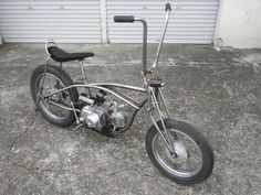 an old chopper bike is parked in front of a garage door