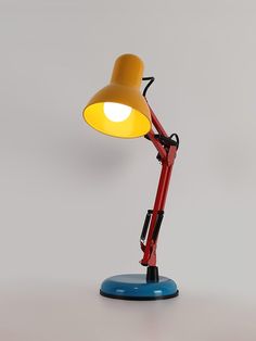 a red and yellow lamp sitting on top of a blue table next to a white wall