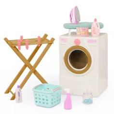 a toy washing machine next to a laundry basket and clothes drying rack on a white background