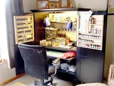 a desk with lots of crafting supplies on it in front of a chair and window