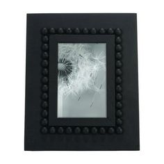 a black frame holds a dandelion with beads on the edges and a white background