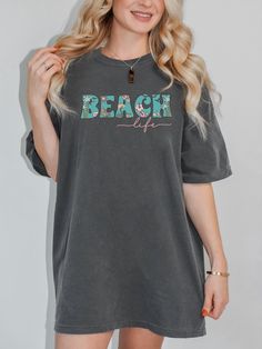 "Get ready to enter vacay mode and enjoy the sunshine this Summer with our cute beach life tee. This t-shirt is available in 4 beautiful colors for you to choose from. It has a relaxed fit and, if you order 2 sizes up from your normal size, you get that trendy oversized look.  KEY FEATURES: *Super comfy 100% ring-spun cotton, without side seams *Medium fabric (6.1 oz/yd² (206.8 g/m *Relaxed fit *Garment-dyed fabric gives a soft feel and colors, for that retro look *Double stitching which makes your cute tee last longer CARE INSTRUCTIONS: *Machine wash: cold (max 30C or 90F) *Do not bleach *Tumble dry: low heat *Iron, steam or dry: low heat *Do not dryclean COLOR DISCLAIMER:  Please note that colors shown in our product images may vary slightly and differ from the final product, as variatio Cute Relaxed Fit T-shirt For Beach Season, Relaxed Fit Beachy Tops For Day Out, Beachy Relaxed Fit Top For Day Out, Relaxed Fit Tops For Beach Season Day Out, Casual T-shirt For Beach Season Day Out, Oversized Beachy Top For Beach Season, Oversized Text Print Tops For The Beach, Oversized Beachy Tops For Spring, Relaxed Short Sleeve Tops For Beach Season