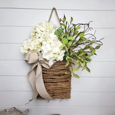 a basket filled with white flowers hanging on a wall