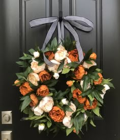 an orange and white wreath on a black door