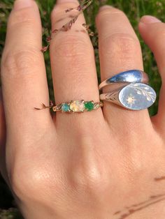 a person's hand with a ring on it and some flowers in the background