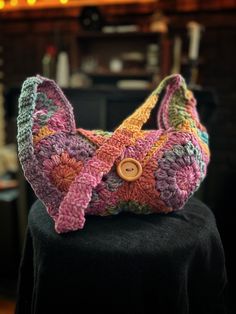 a crocheted purse sitting on top of a black table next to a fireplace