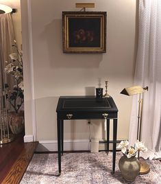 a small black table sitting on top of a rug in a living room next to a painting