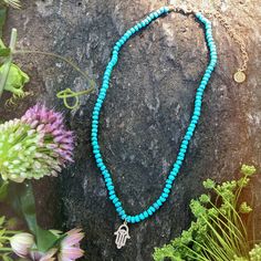 Turquoise is called the self acceptance stone. It promoted self-esteem and unconditional love. Our hand beaded necklace also has a Hamsa charm pendant in goldtone plated brass with cubic zirconia stones. The Hamsa symbol dates back to ancient Mesopotamia where the open right hand is seen in artifacts and in the amulets of the goddess Ishtar. Other symbols of divine protection based around the hand include the Hand-of-Venus which was used to protect women from the evil eye and/or boost fertility, Holistic Turquoise Necklaces With Natural Stones, Bohemian Turquoise Evil Eye Necklace, Spiritual Turquoise Necklaces For Festivals, Handmade Blue Turquoise Necklace For Meditation, Handmade Turquoise Spiritual Necklace, Turquoise Pendant Beaded Necklace For Meditation, Handmade Turquoise Beaded Necklaces For Meditation, Spiritual Turquoise Necklace For Meditation, Handmade Turquoise Necklace For Meditation