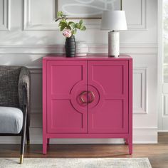 a pink cabinet next to a gray chair in a room with white walls and flooring