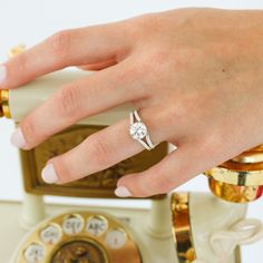 a woman's hand with a diamond ring on top of an old fashioned telephone