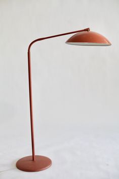 an orange floor lamp on a white background with the light turned off and dimmed