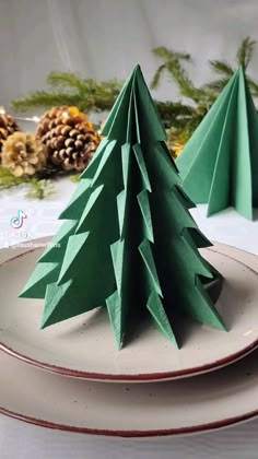 paper christmas trees on plates with pine cones in the background