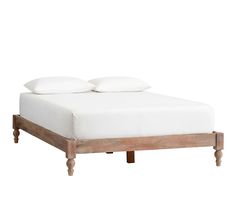 a bed with two white pillows on top of it and some wooden legs around the headboard