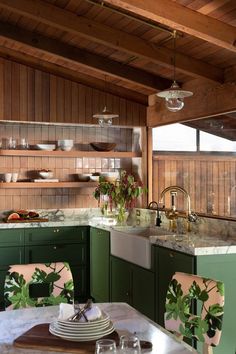 a kitchen with green cabinets and marble counter tops