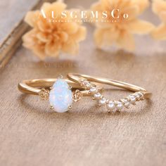 two gold rings with white opal and pearl beads on the side, sitting next to each other