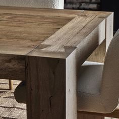 a wooden table with two chairs and a rug on the floor in front of it